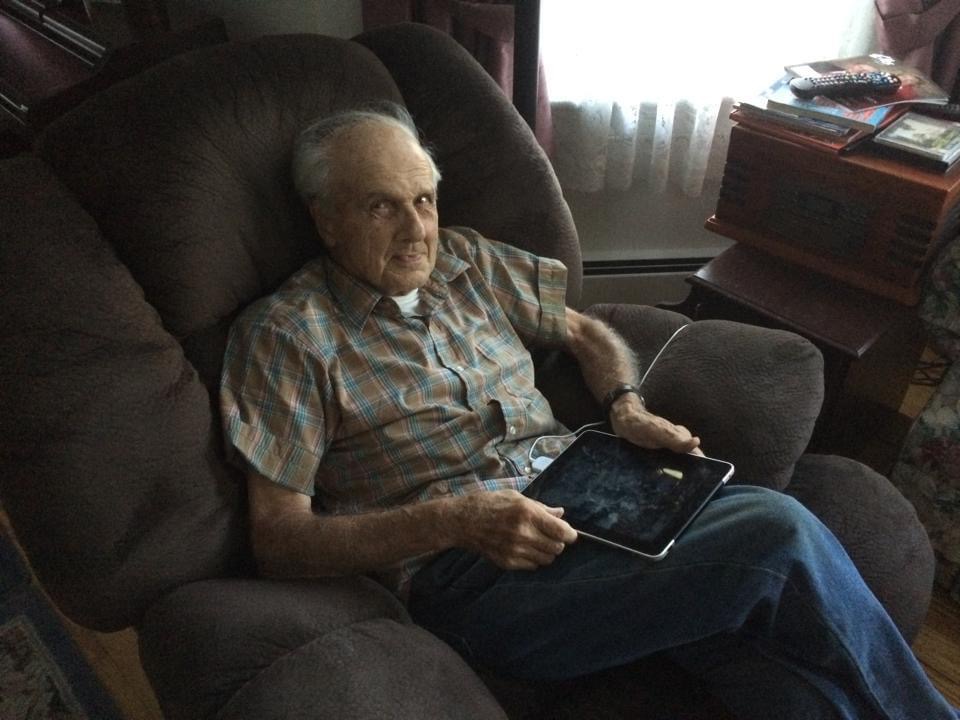 Dick Hann seated in his living room holding an iPad